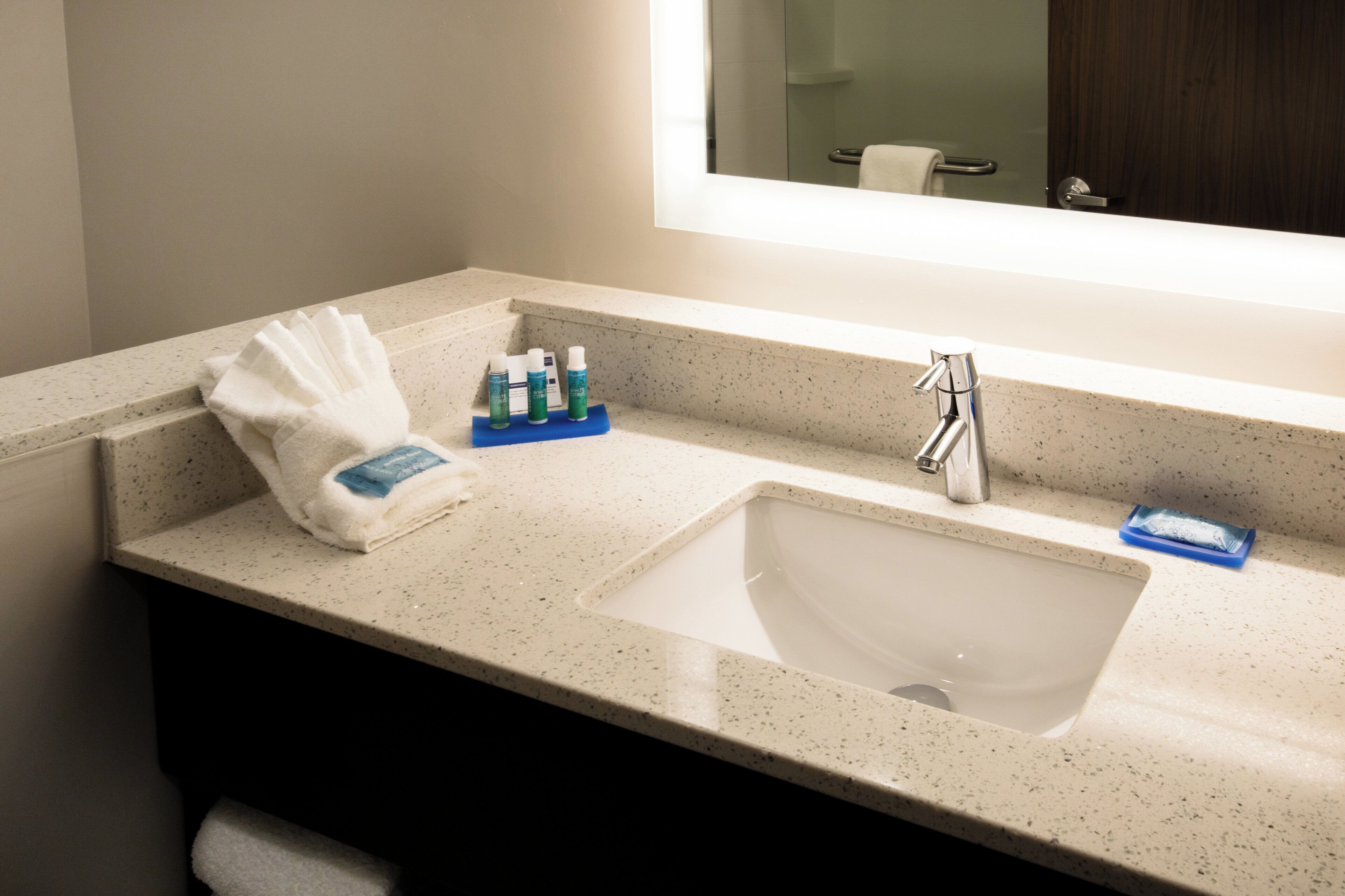 A bathroom with a sink, mirror, and toiletries.