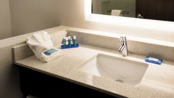 A bathroom with a sink, mirror, and toiletries.