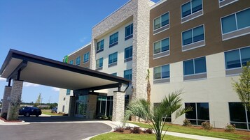 A multi-story hotel with a covered entrance, stone facade, and large windows.