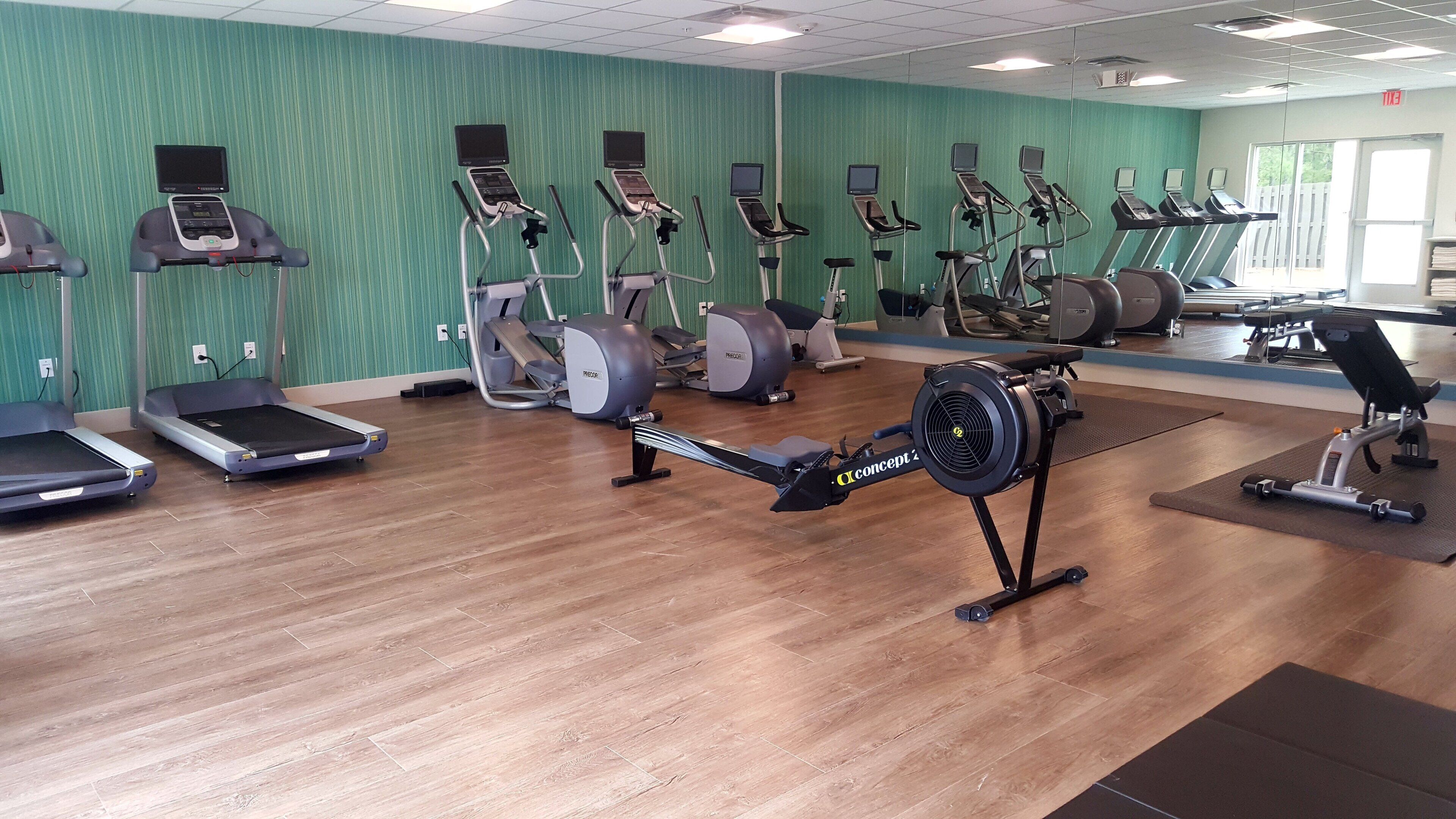 Academia com diversos equipamentos de exercício, incluindo esteiras, bicicletas ergométricas e remo.