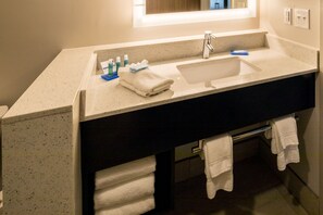 Une salle de bain avec un grand lavabo, un miroir et un porte-serviettes.