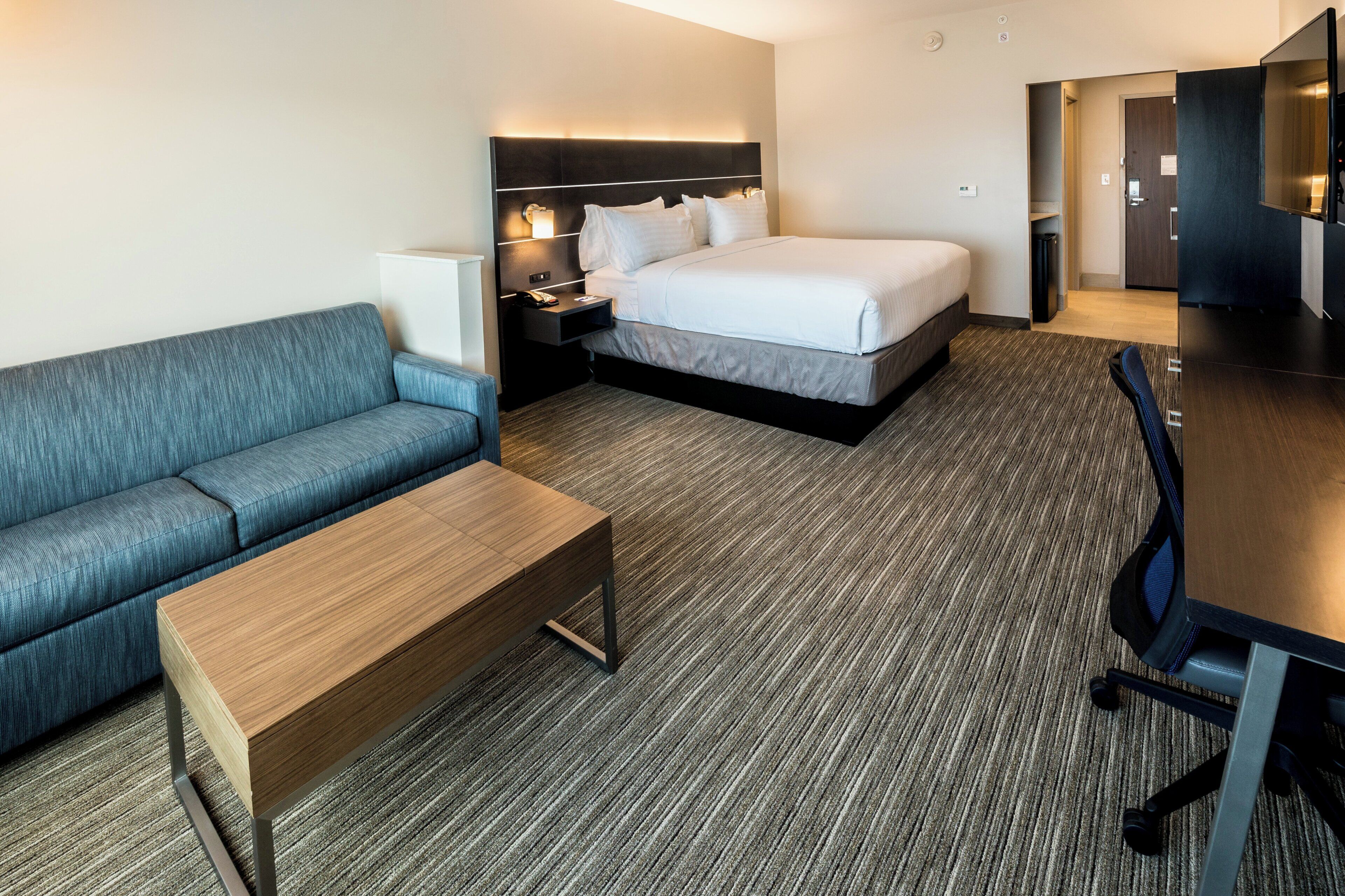 Een hotelkamer met een bank, een bed, een bureau en een stoel.