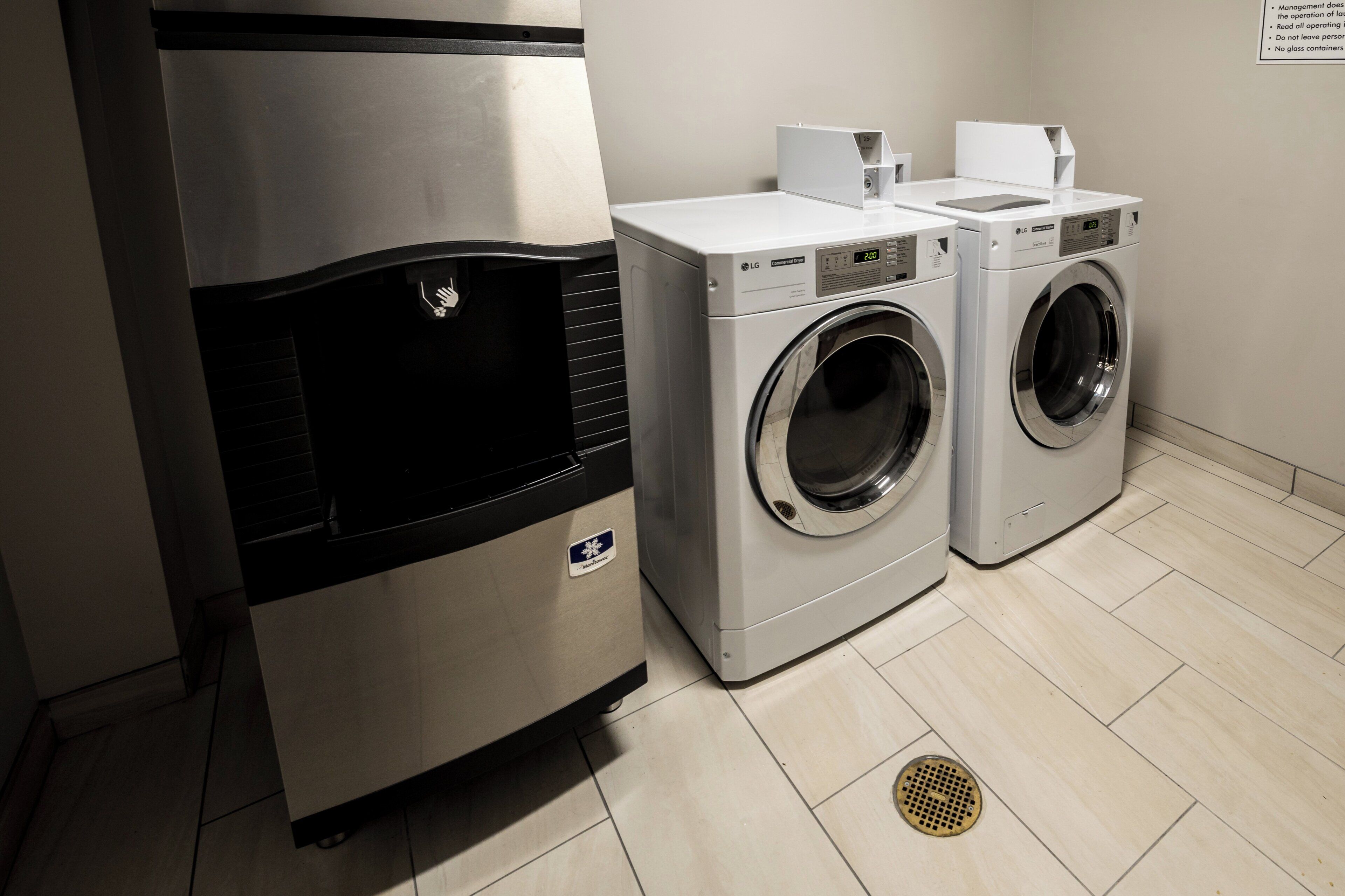 A laundry area with two front-loading washing machines and a stainless steel refrigerator.
