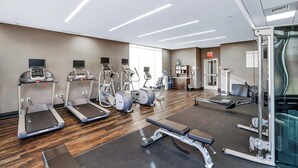 Un gimnasio con cintas de correr, elípticas y equipo de levantamiento de pesas.