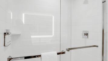 Una cabina doccia in vetro con soffione manuale, un porta asciugamani e un pannello di controllo.