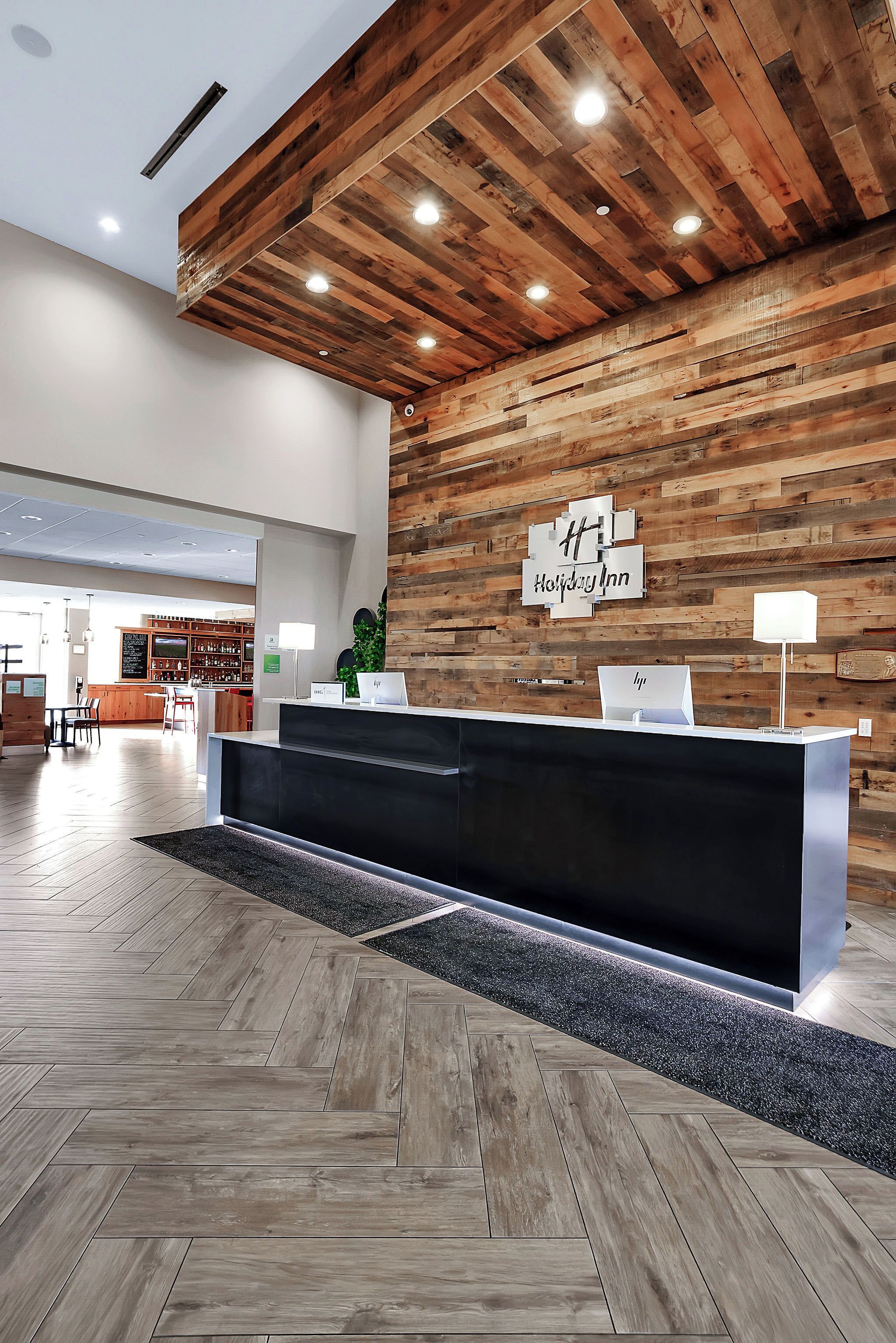 A reception area with a wooden wall, a reception desk, and a bar area in the background.
