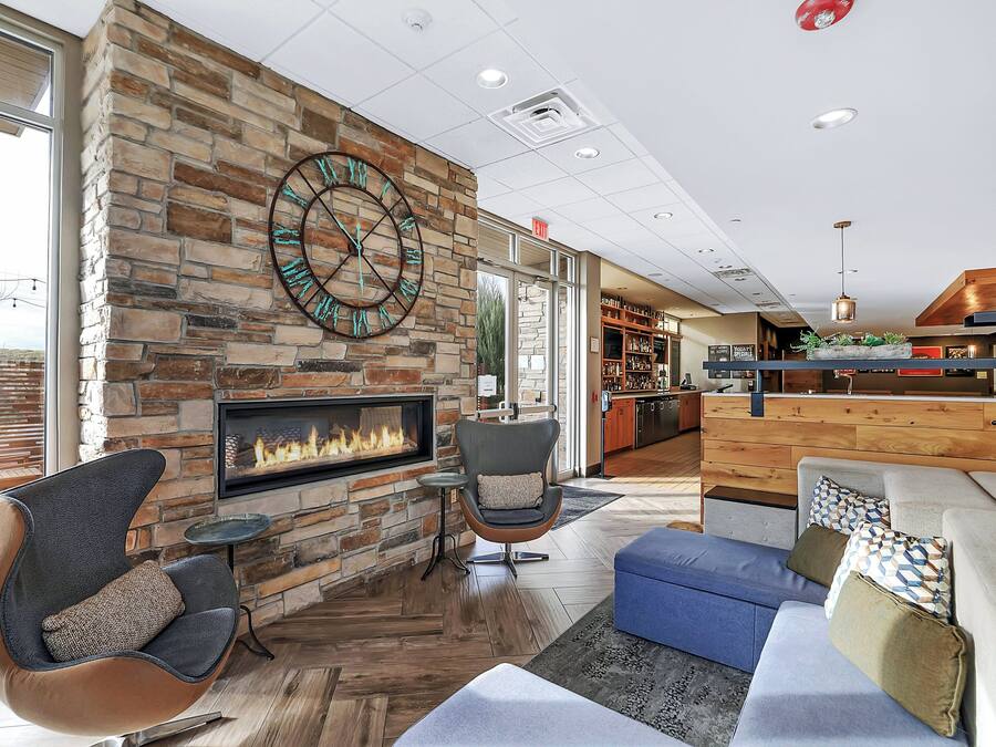 A modern lounge area with a stone fireplace, comfortable seating, and a large wall clock.