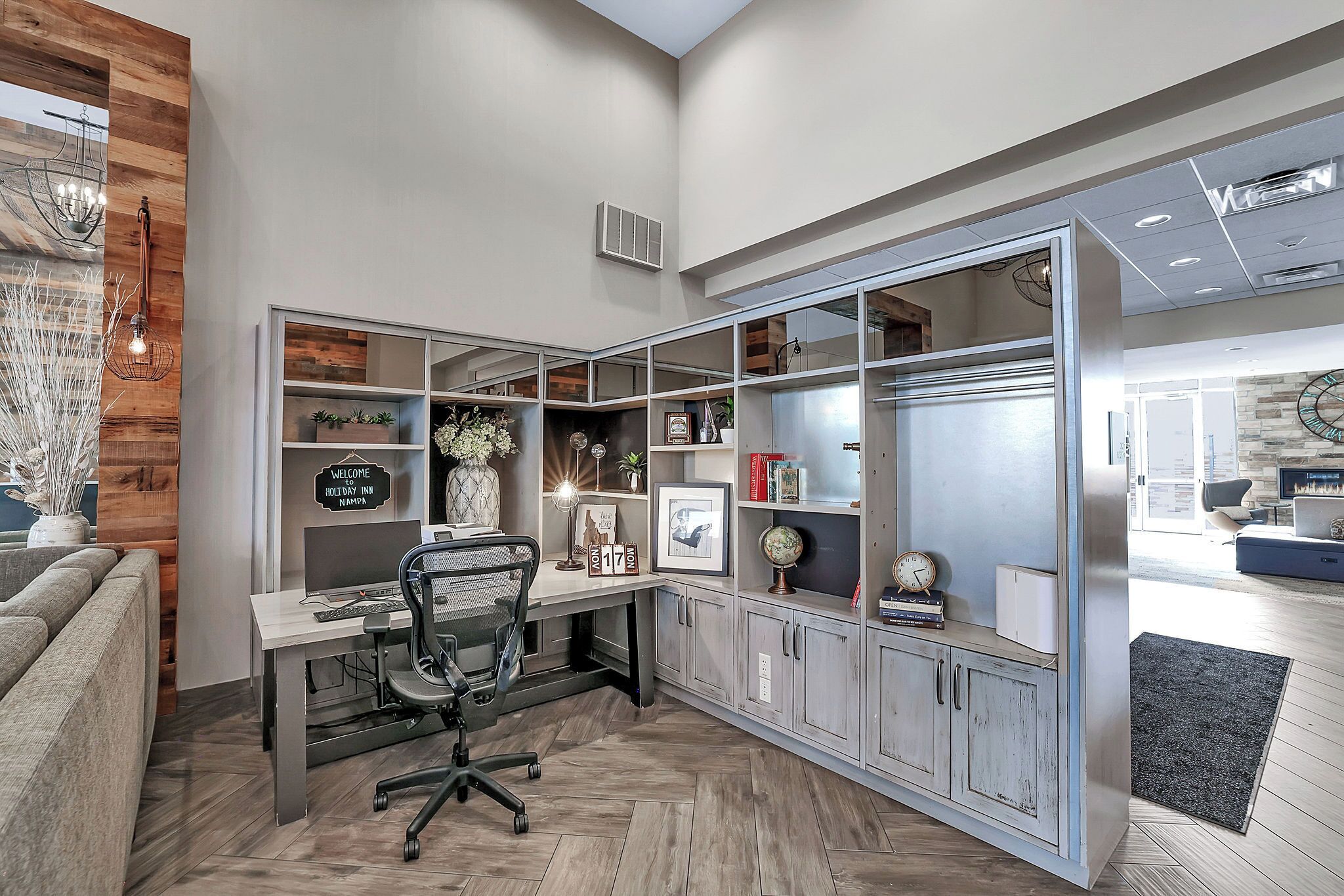 A modern office space with a desk, office chair, shelves with decorative items, and a large window.