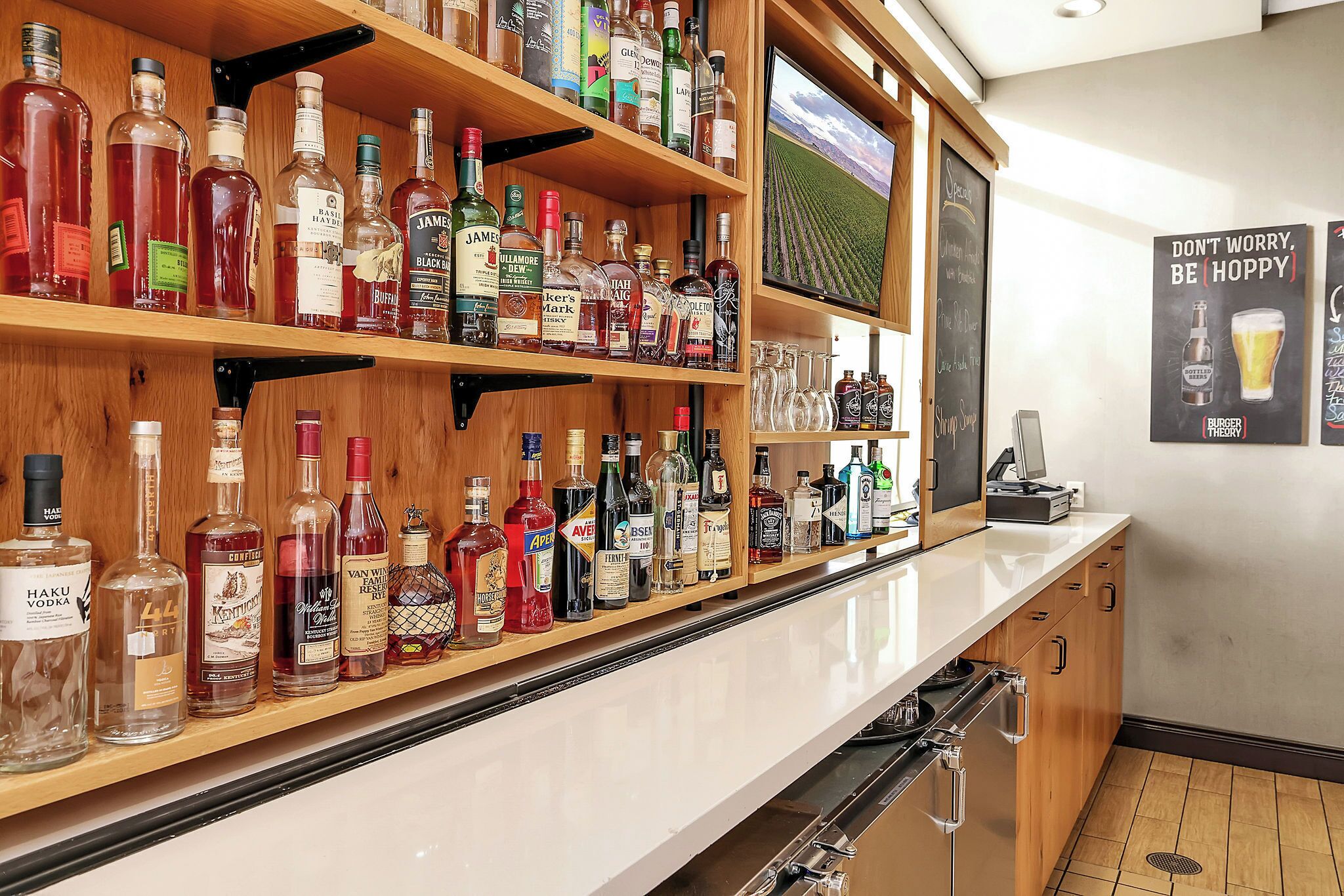 A bar area with shelves of various liquor bottles and a television screen.