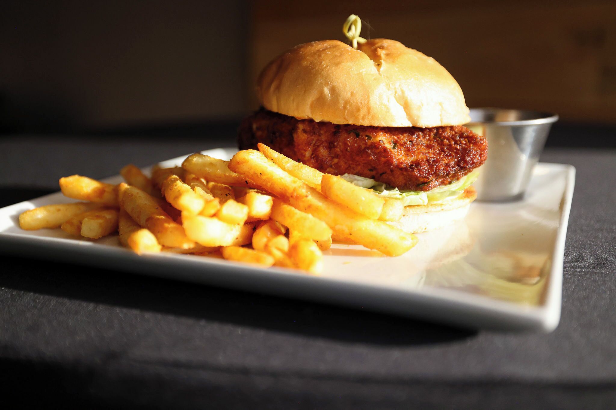 Een bord met een kipburger en friet.