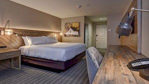 Una habitación de hotel con una cama, mesita de noche, lámpara y un cuadro en la pared.