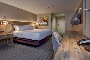 A hotel room with a bed, bedside table, lamp, and a painting on the wall. - Holiday Inn Nampa by IHG (Nampa)