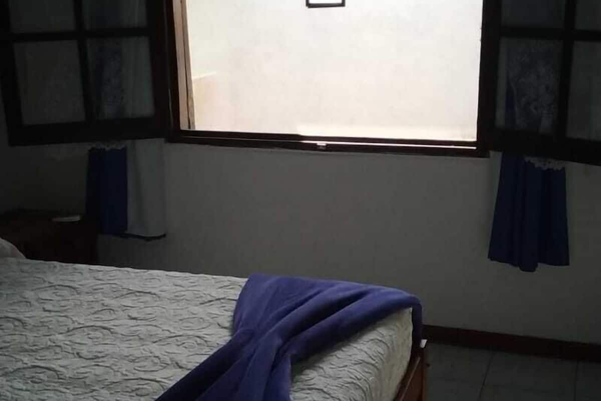 A bedroom with a bed, a window, and curtains.