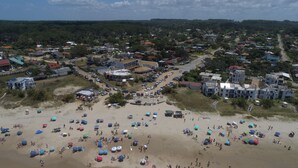An aerial view of a coastal town with a beach area featuring numerous umbrellas and people. - Bungalows Los Lucianos del Piemonte (La Paloma)