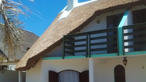 A house with a thatched roof, a balcony with a green railing, and a chimney. - Bungalows Los Lucianos del Piemonte (La Paloma)