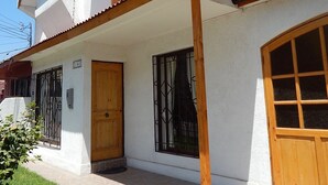 Una casa de dos pisos con un balcón, una puerta de madera y una ventana con rejas.