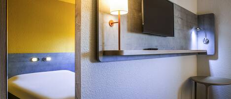 A modern bathroom with a bed, a mounted TV, and a wall-mounted light fixture.