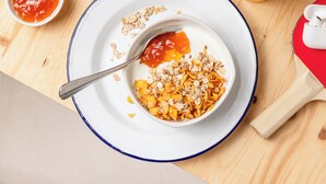 A breakfast setting with a bowl of cereal, a spoon, and a small bowl of ketchup. - ibis budget Fontainebleau Avon (Avon)