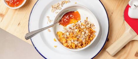 Desayuno con un tazón de cereal, una cuchara y un recipiente pequeño de kétchup.