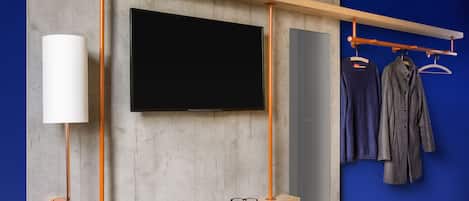Una habitación moderna con televisión montada, estante de madera, perchero y lámpara.