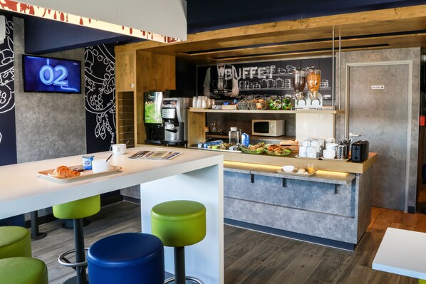 A modern kitchen area with a bar counter, stools, and a coffee machine.