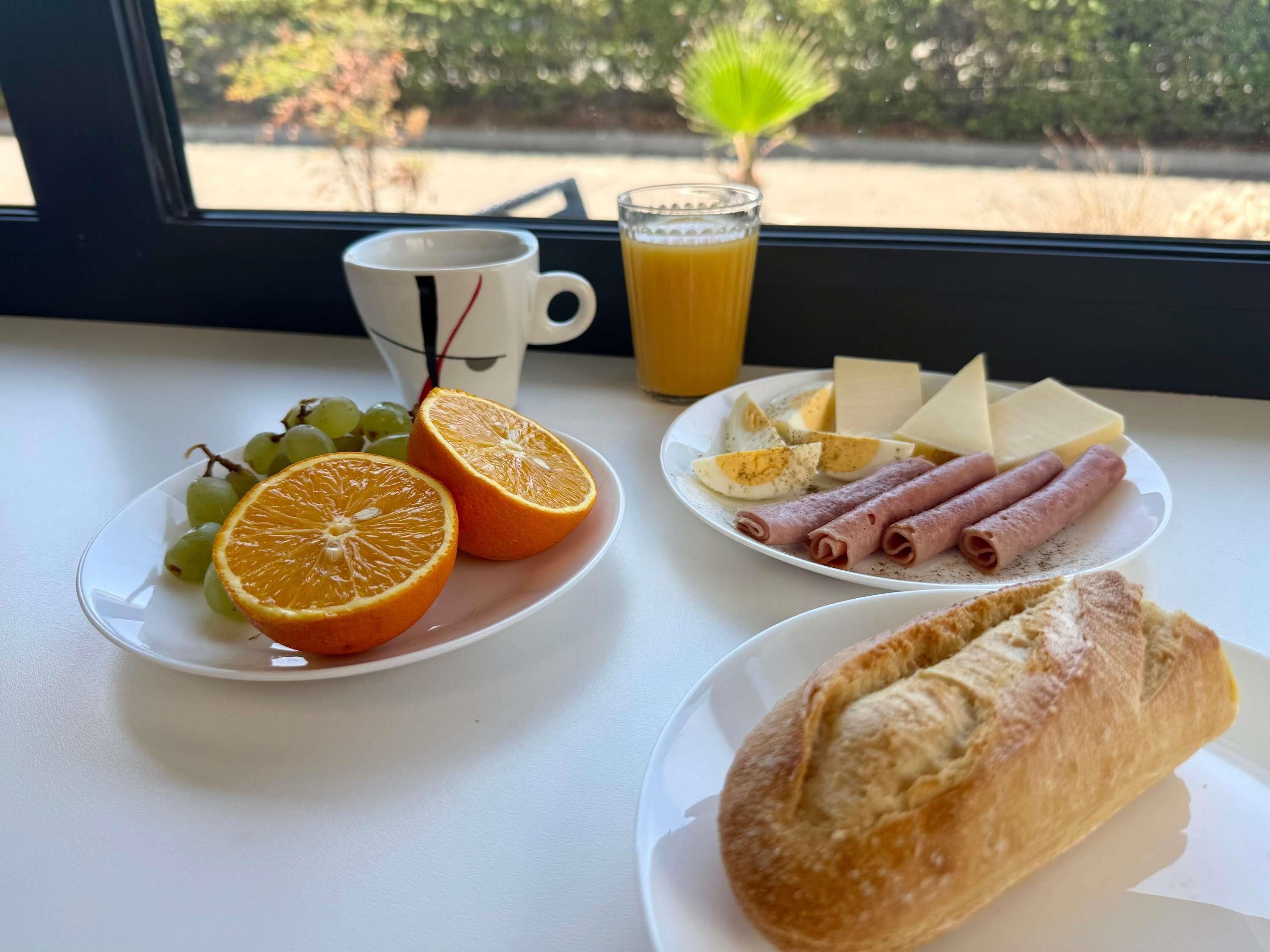 A breakfast setting with a plate of food, a cup, and a glass of orange juice.