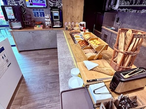 A breakfast buffet with various food items and a coffee machine. - ibis budget Marseille Vitrolles (Vitrolles)