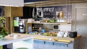 Una colazione moderna con macchina del caffè, forno a microonde e diverse opzioni alimentari.