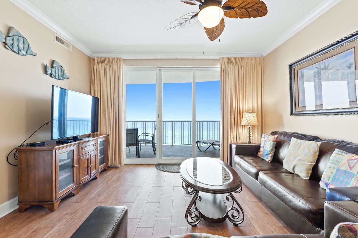 A living room with a television, wooden cabinet, leather sofa, and a glass table.