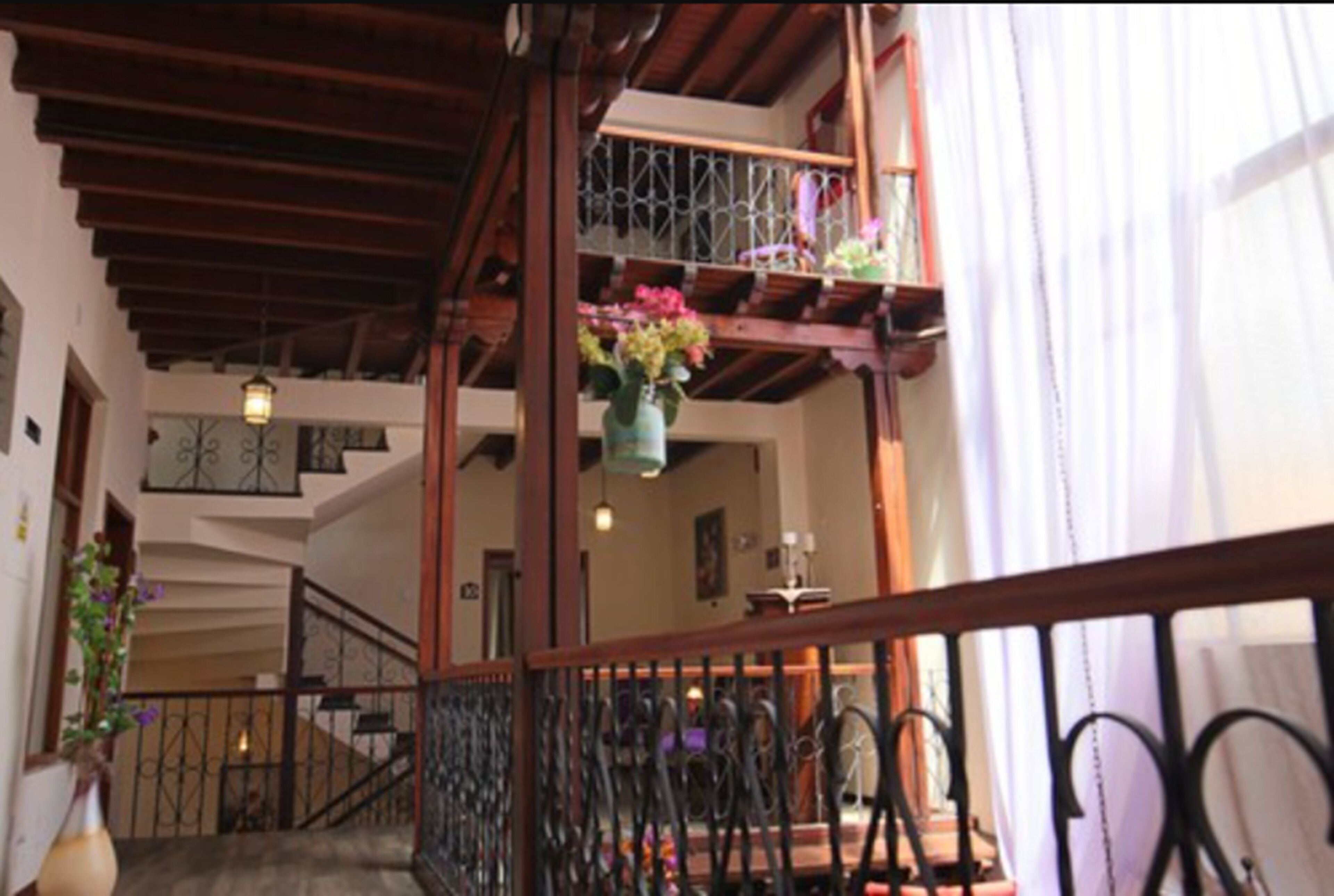 A wooden staircase with a wrought iron railing, leading to a balcony with hanging flower baskets.