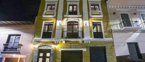 Un hotel con fachada clásica, que presenta una entrada destacada con un arco decorativo y un letrero que dice "San Agustin Hotel Boutique".