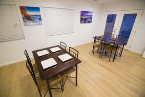 A dining area with a wooden table and chairs, white plates, and a cityscape painting on the wall. - Los Angeles RoomRentals LAX (Los Angeles)