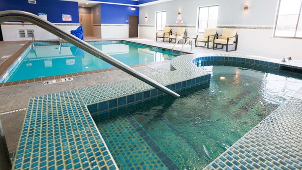 Piscina interior com água cristalina, plataforma de mergulho e espreguiçadeiras.