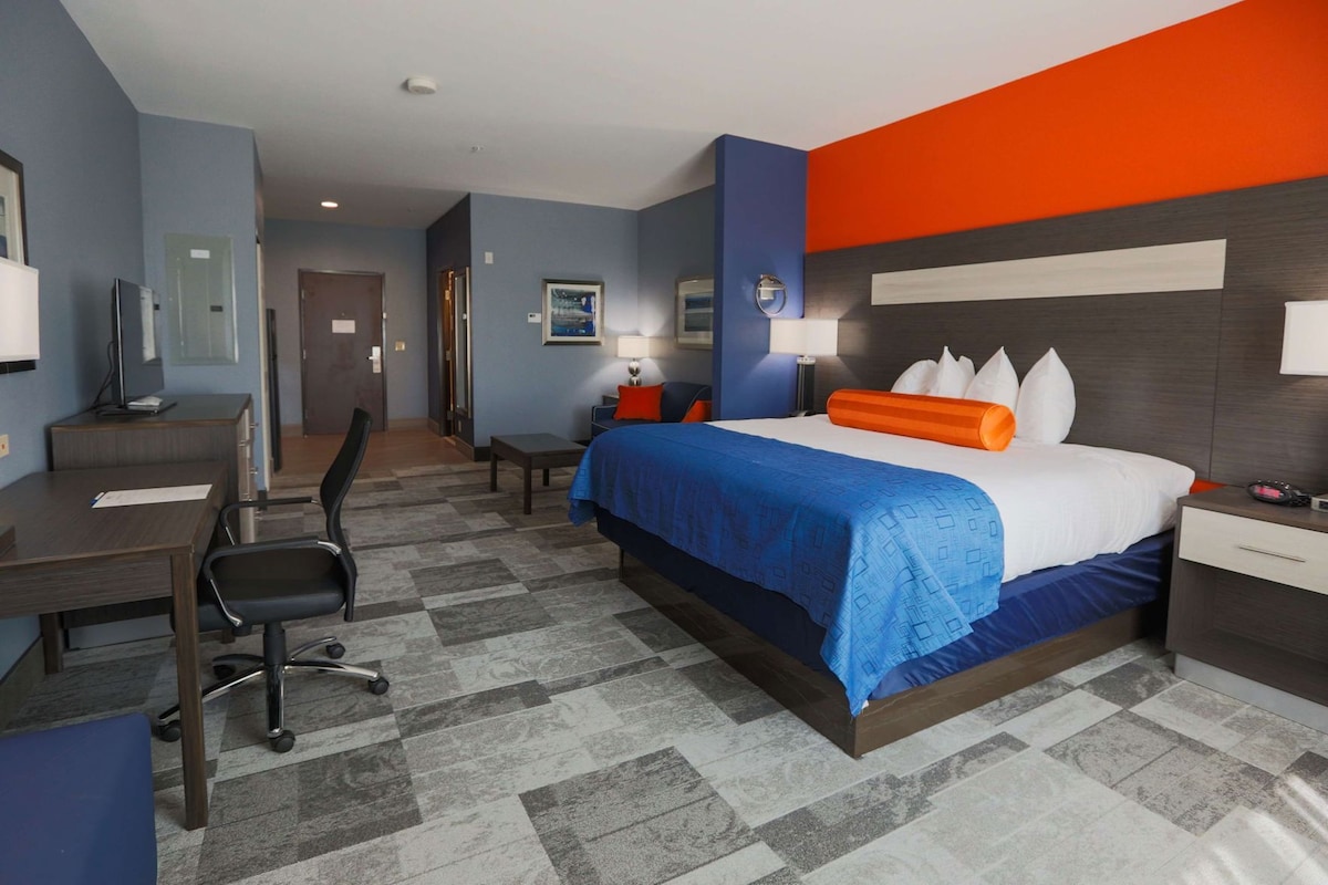 A hotel room with a bed, desk, chair, and a small table.