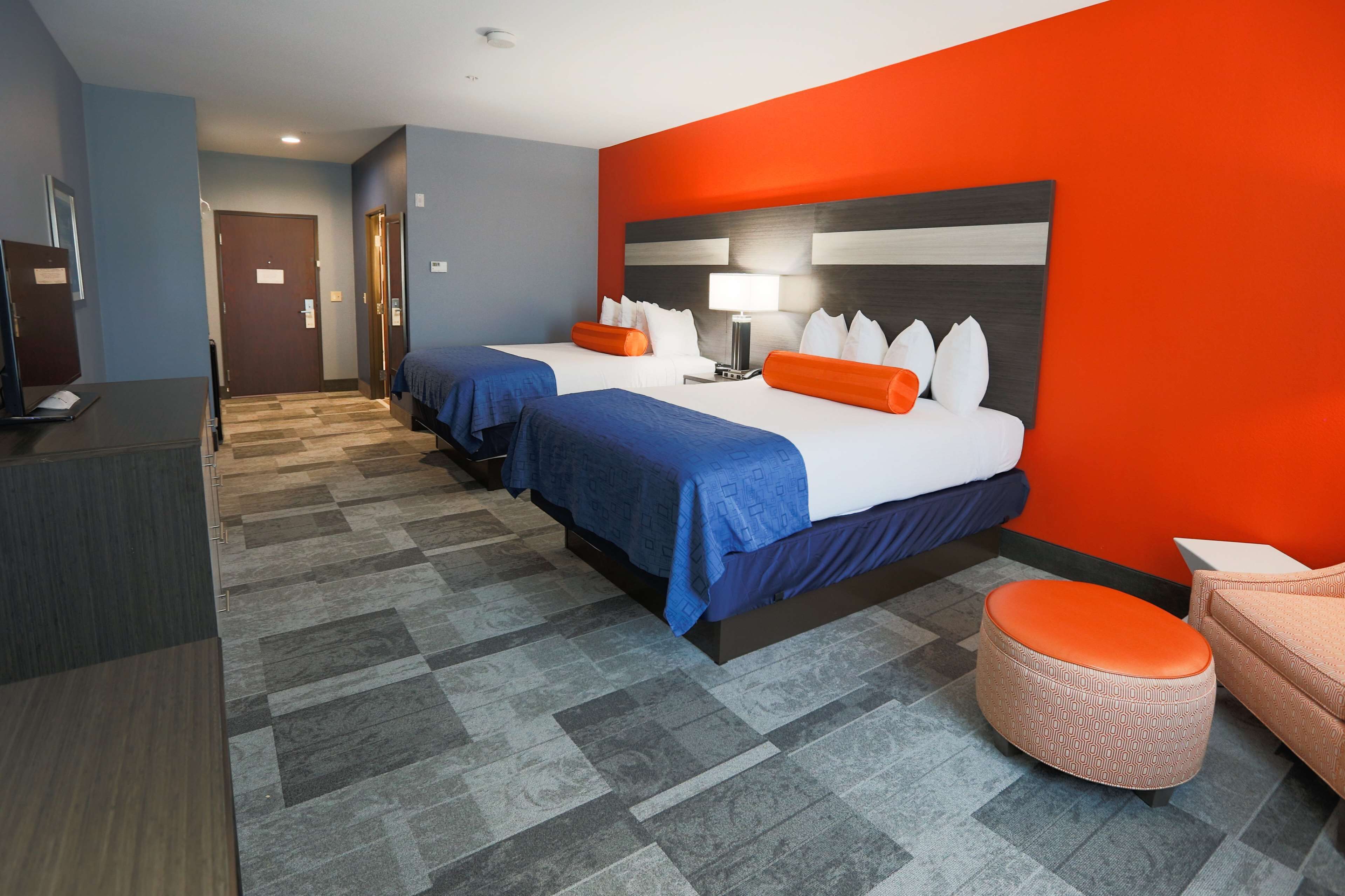 A hotel room with two beds, a desk, and a chair.