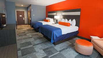 A hotel room with two beds, a desk, and a chair.