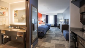 Quarto de hotel com banheiro, uma cama, escrivaninha e televisão.