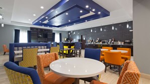 Uma área de estar moderna com assentos, um bar e uma televisão.