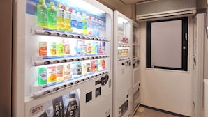 Una máquina expendedora con diversas bebidas y aperitivos, incluyendo refrescos y café instantáneo.