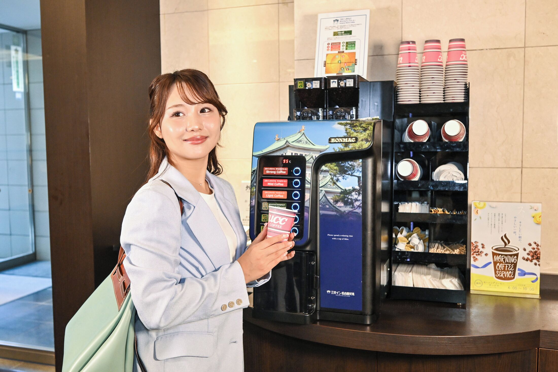 A coffee machine with options for strong, light, and hot coffee, and a display of coffee cups and saucers.