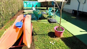 A patio with kayaks, a small tree, and a mural on the wall. - Te Ava Piti Lodge (Raiatea)