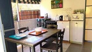 A compact kitchen with a dining area, a refrigerator, a microwave, and a stove. - Te Ava Piti Lodge (Raiatea)
