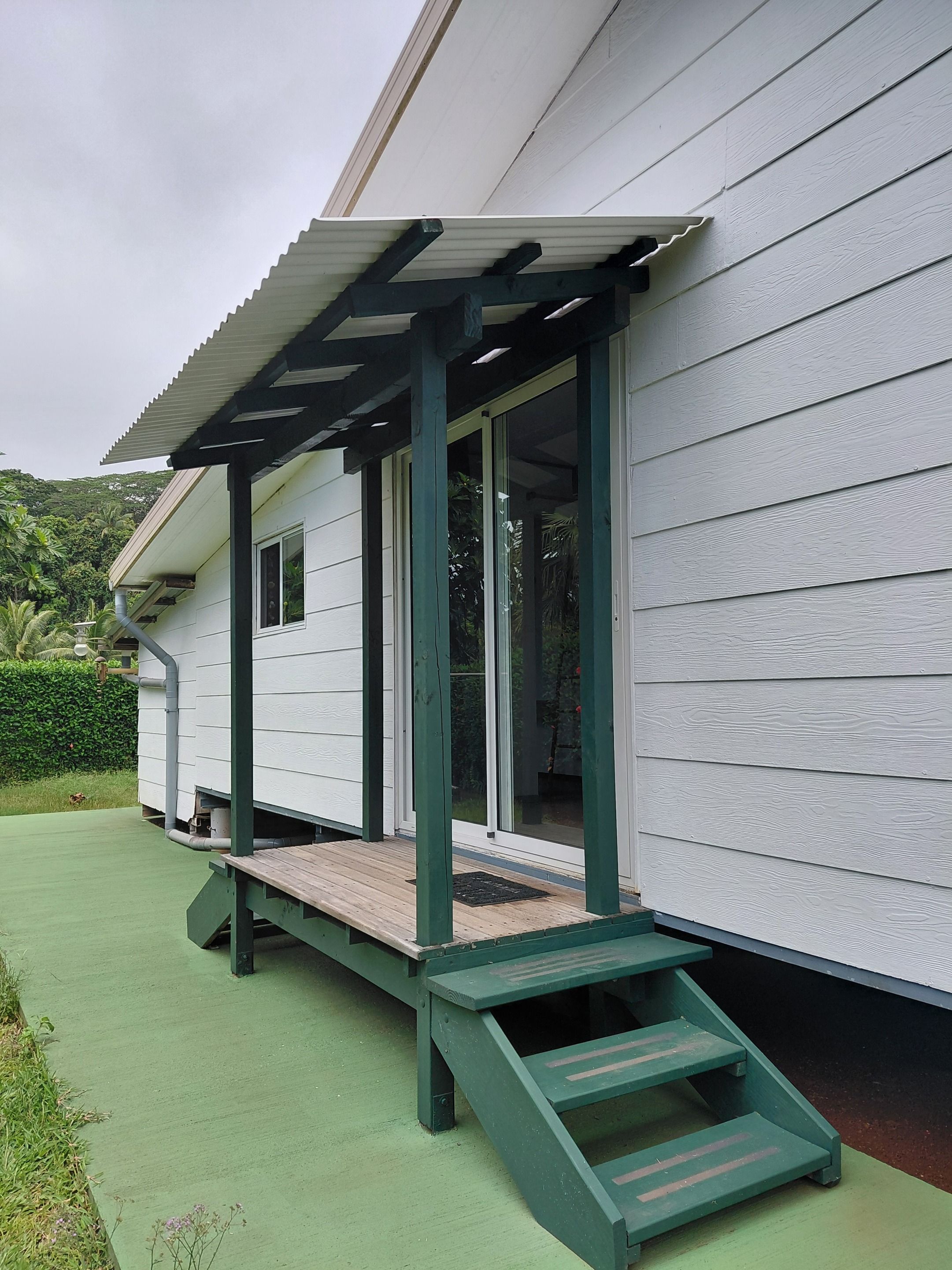 Ein Haus mit einer überdachten Veranda und einer grünen Terrasse.