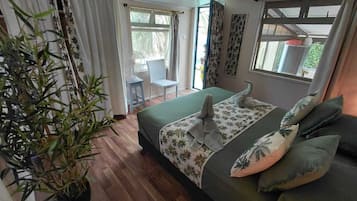 Een slaapkamer met een bed, een kamerplant, een stoel en een raam.