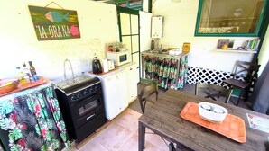 A compact kitchen with a stove, microwave, and small dining area. - Te Ava Piti Lodge (Raiatea)