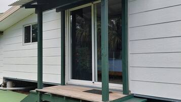 A house with a covered porch, a green ramp, and a window with a view of palm trees.
