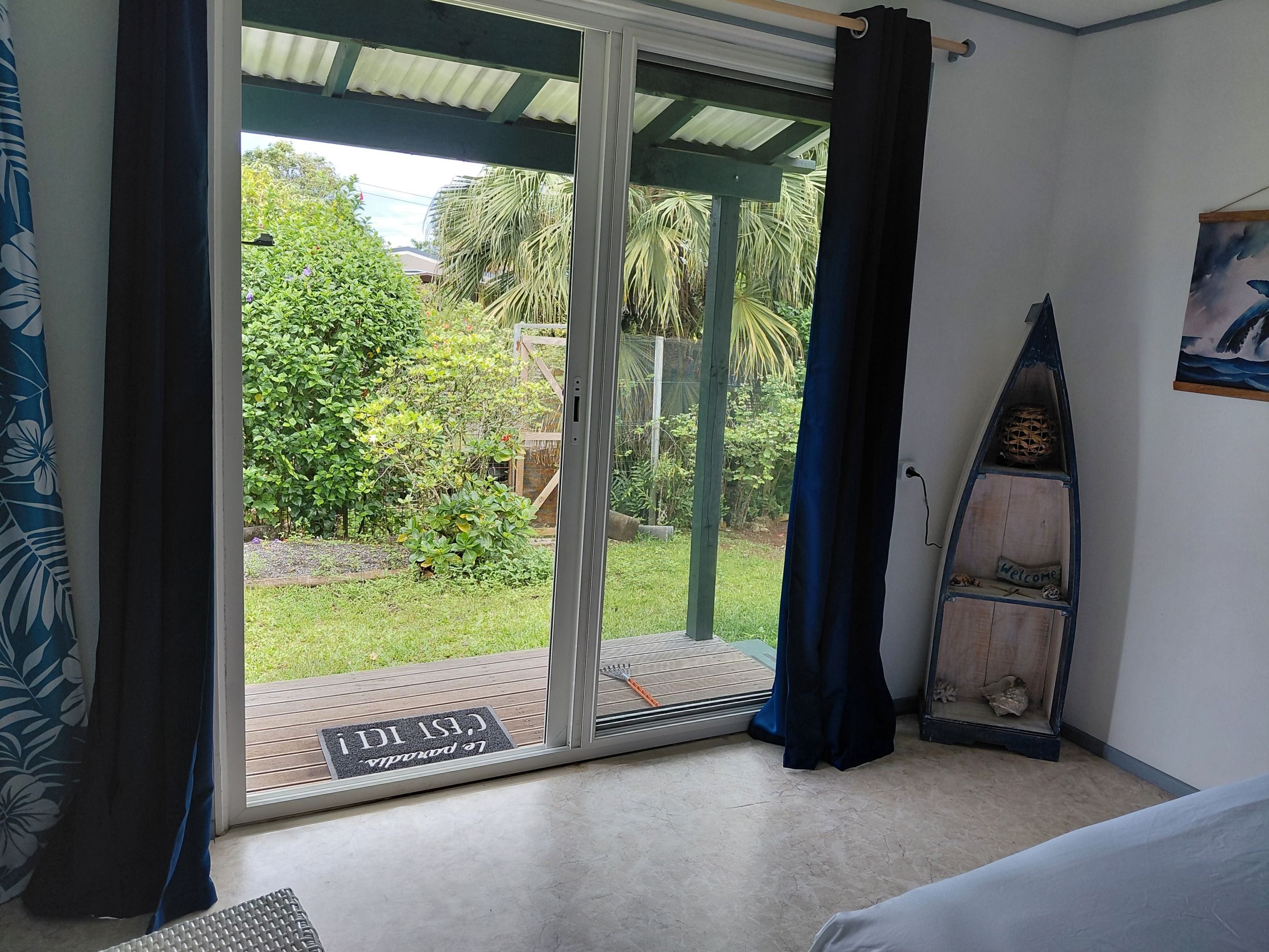A room with a sliding glass door leading to a balcony, a surfboard, and a welcome mat.