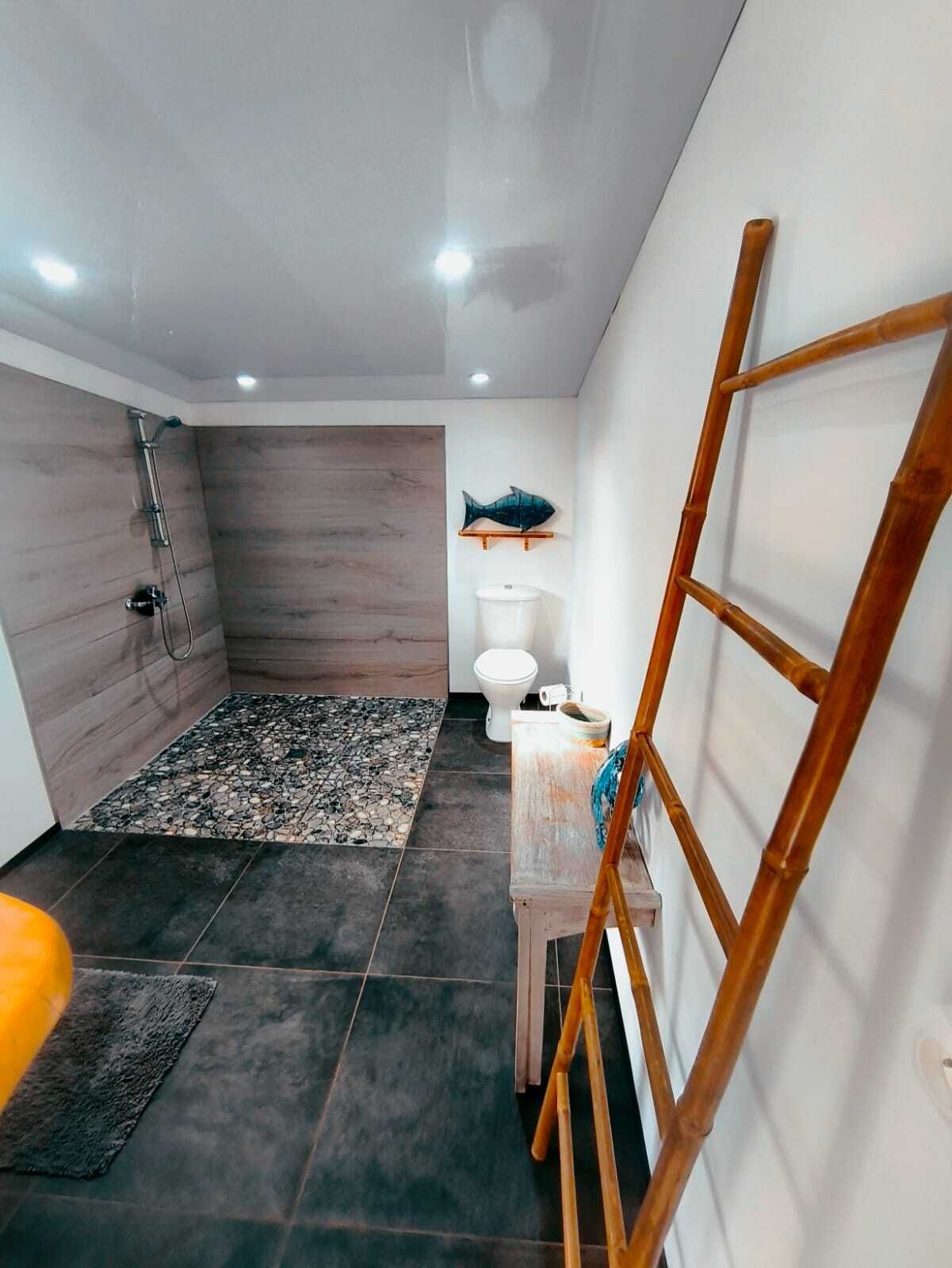 Une salle de bain avec une douche, des toilettes et une petite table sur laquelle est posée une serviette.