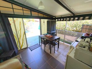 A dining area with a table and chairs, a microwave, and a small kitchen area with a refrigerator. - Te Ava Piti Lodge (Raiatea)