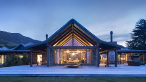 A modern lodge with a prominent triangular roof, large windows, and a spacious patio area. - Mahu Whenua (Treble Cone)